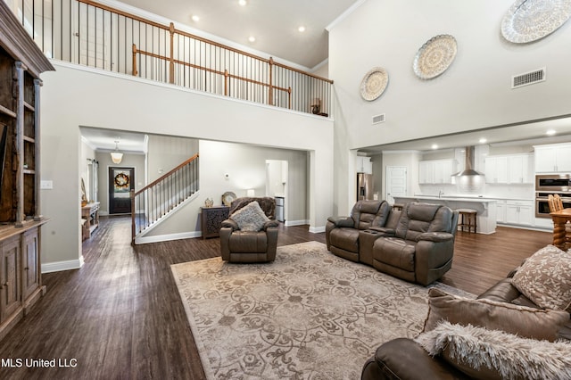 living room with ornamental molding, a high ceiling, and hardwood / wood-style floors