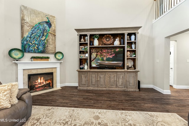 living room with hardwood / wood-style flooring, a high ceiling, and a fireplace