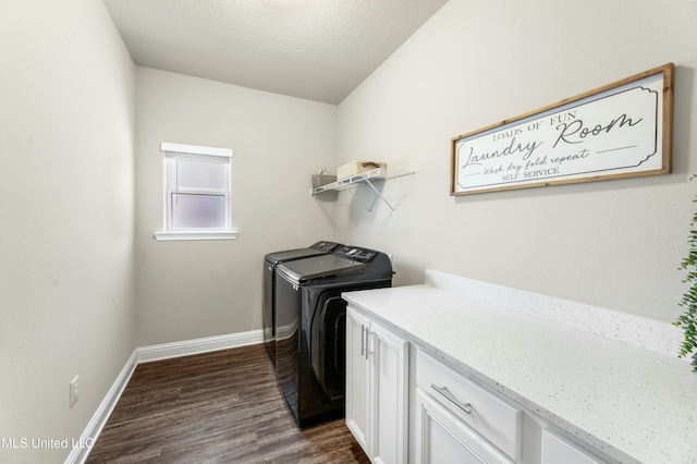 laundry room featuring washing machine and clothes dryer, dark wood-type flooring, cabinets, and a textured ceiling