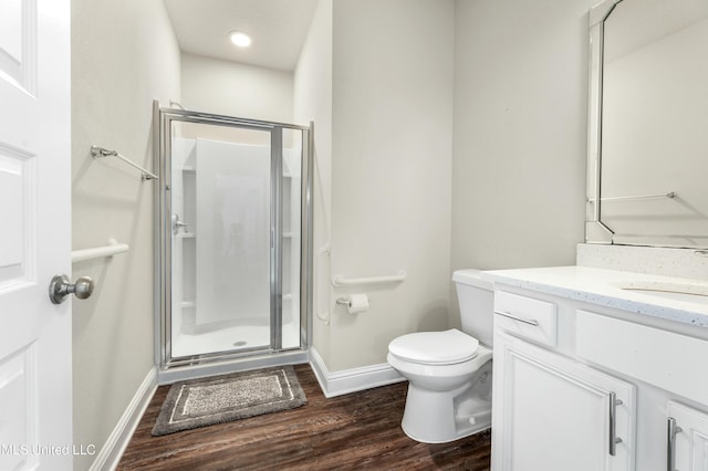 bathroom featuring toilet, wood-type flooring, vanity, and a shower with door