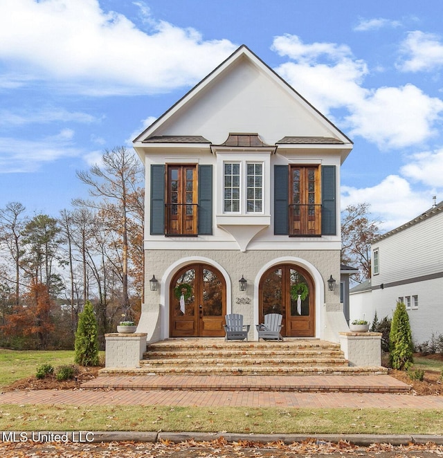 view of front facade featuring french doors, a balcony, and a porch