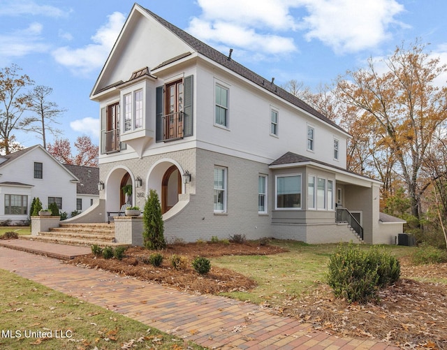 view of front of property featuring central AC unit, a balcony, and a front yard