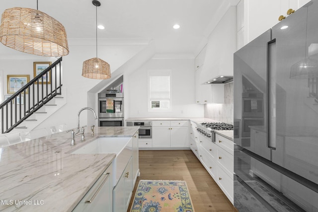 kitchen featuring white cabinetry, ornamental molding, hanging light fixtures, and appliances with stainless steel finishes