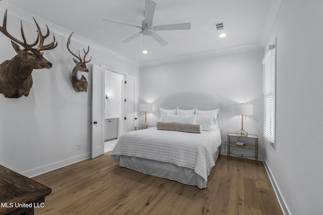 bedroom with connected bathroom, hardwood / wood-style flooring, ceiling fan, and ornamental molding