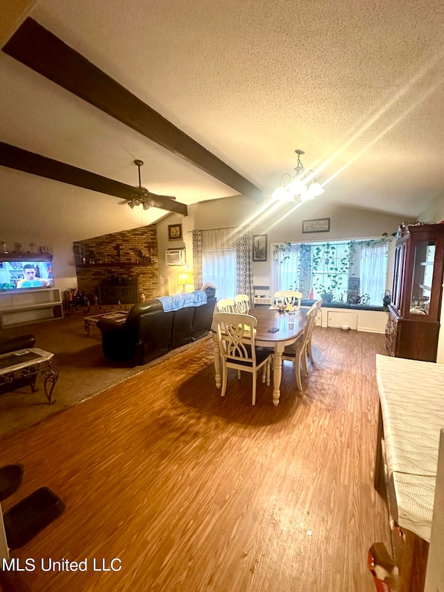 2236 Long St, Grenada, MS 38901 - dining space with a textured ceiling, wood-type flooring, ceiling fan with notable chandelier, a fireplace, and lofted ceiling with beams