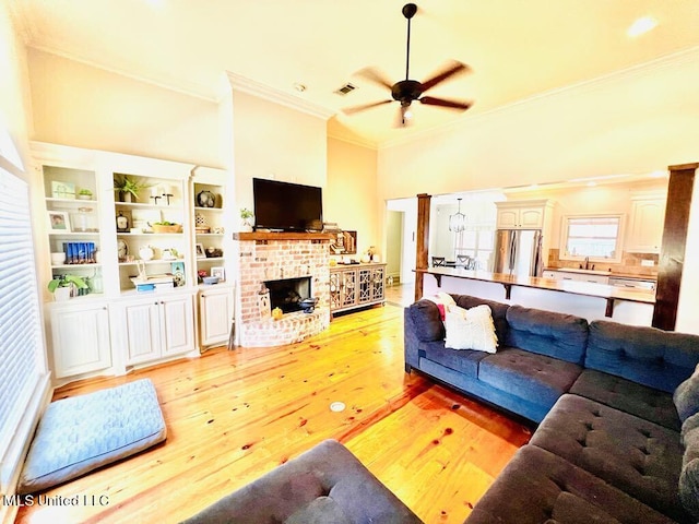 living room featuring ceiling fan, light hardwood / wood-style floors, ornamental molding, and a fireplace