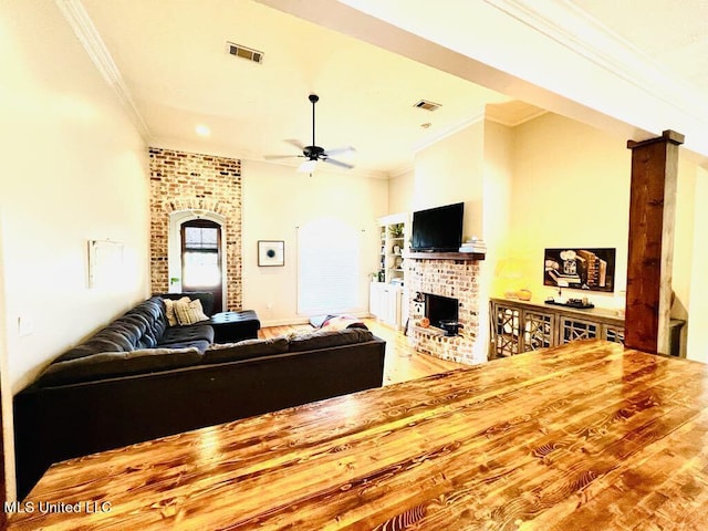 living room with wood-type flooring, a brick fireplace, ceiling fan, and ornamental molding