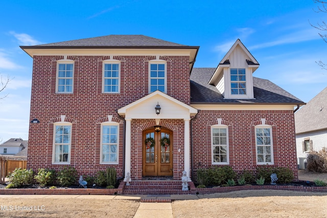 view of front facade featuring french doors, brick siding, central AC unit, and a shingled roof