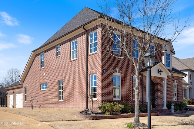 view of home's exterior featuring a garage, brick siding, and driveway