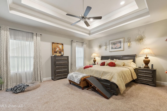 bedroom with a raised ceiling, carpet, crown molding, baseboards, and a ceiling fan