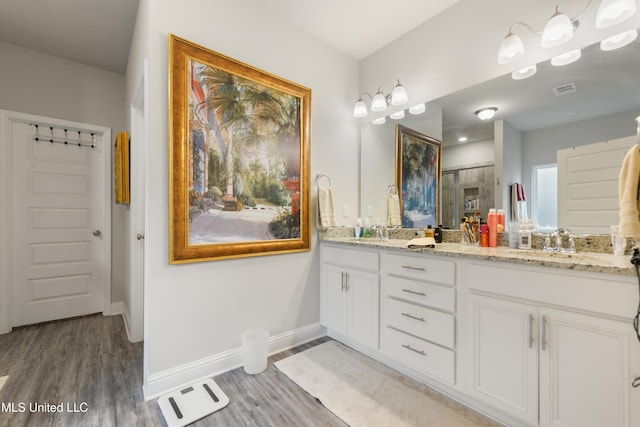 bathroom featuring wood finished floors, baseboards, and double vanity