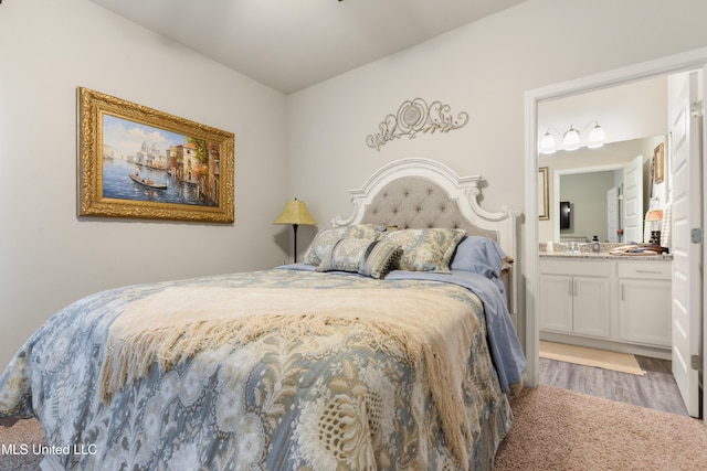 bedroom featuring wood finished floors and ensuite bath
