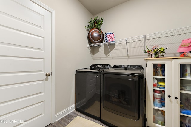washroom with washer and dryer, wood finished floors, and baseboards