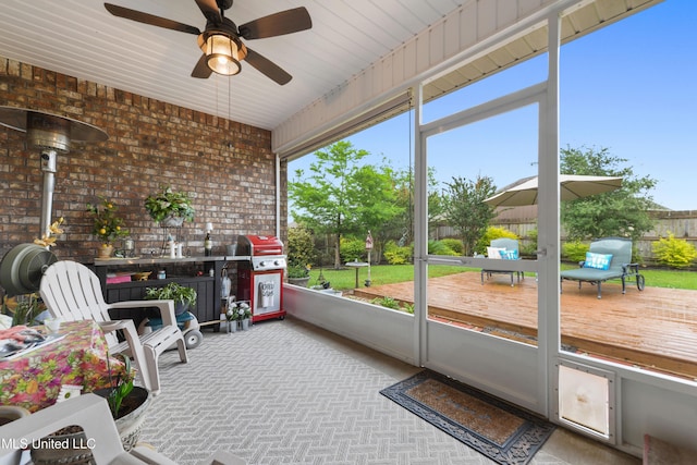 sunroom featuring ceiling fan and a wood stove