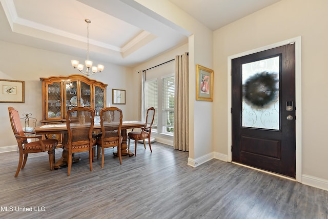 dining room with wood finished floors, a chandelier, baseboards, and a raised ceiling