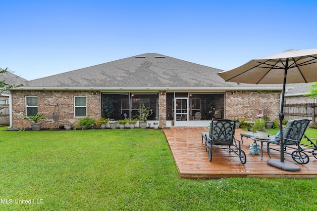 rear view of property featuring a wooden deck, brick siding, a sunroom, and roof with shingles