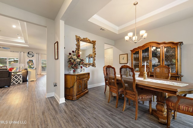 dining space with a tray ceiling, dark wood finished floors, a chandelier, baseboards, and recessed lighting