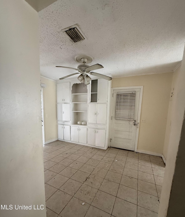 unfurnished living room featuring ceiling fan, light tile patterned flooring, ornamental molding, and a textured ceiling