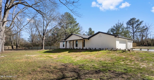 exterior space with a garage, a lawn, fence, and stucco siding