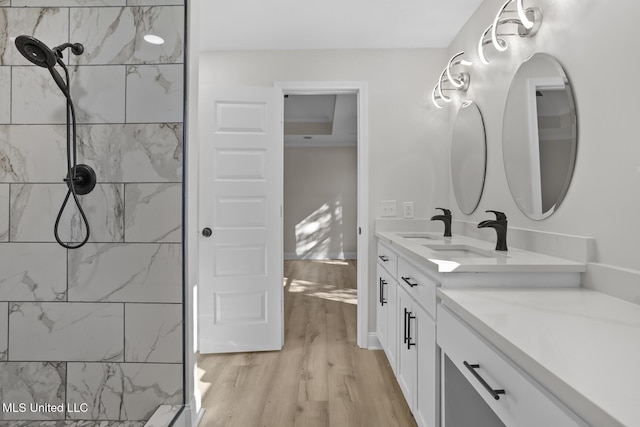 bathroom with vanity, tiled shower, and wood finished floors