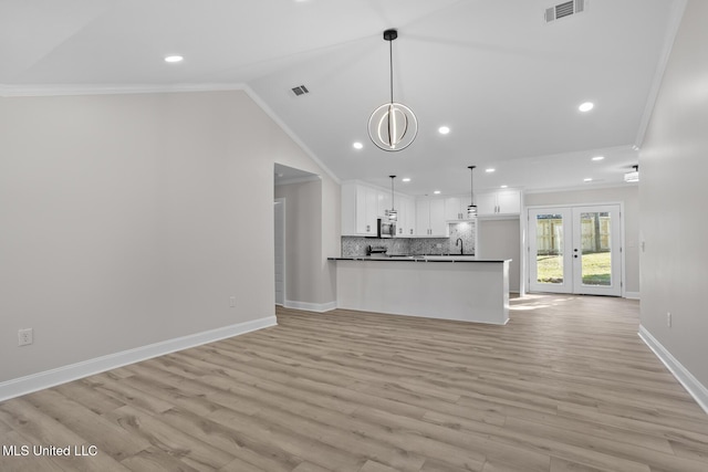 unfurnished living room featuring visible vents, baseboards, vaulted ceiling, french doors, and ornamental molding