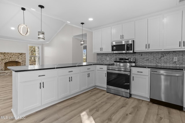 kitchen featuring plenty of natural light, a peninsula, appliances with stainless steel finishes, and dark countertops