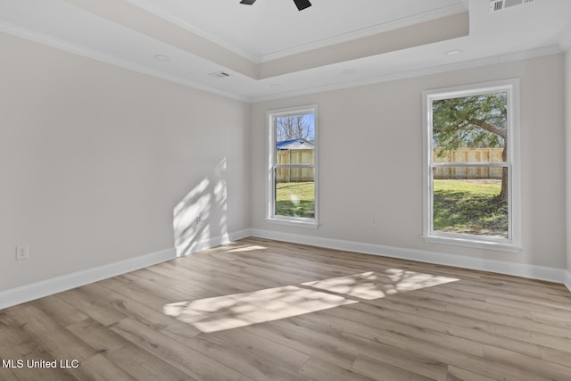 empty room with wood finished floors, ornamental molding, a raised ceiling, and visible vents