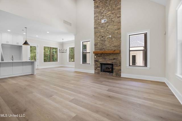 563 Valentine Rd, Holly Springs, MS 38635 - unfurnished living room with light wood-style flooring, a fireplace, high vaulted ceiling, a chandelier, and recessed lighting