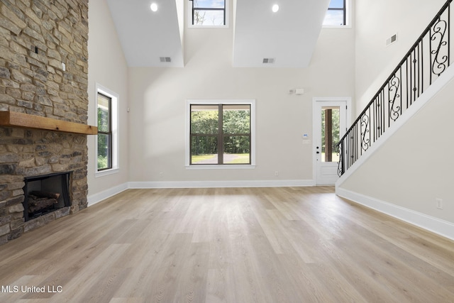 563 Valentine Rd, Holly Springs, MS 38635 - unfurnished living room featuring high vaulted ceiling, plenty of natural light, a stone fireplace, light wood-style flooring, and stairs