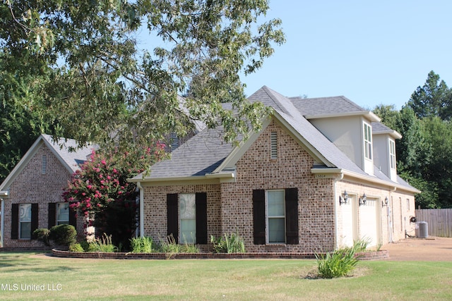 traditional-style house featuring central AC unit, an attached garage, brick siding, driveway, and a front yard