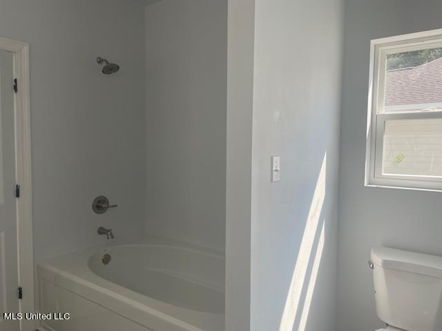 bathroom featuring toilet, washtub / shower combination, and a wealth of natural light