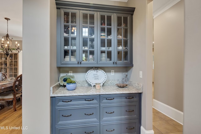 bar area with a chandelier, light tile patterned floors, baseboards, hanging light fixtures, and ornamental molding
