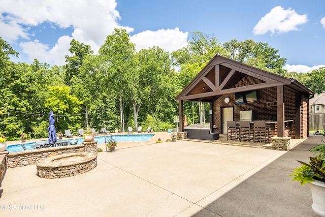 outdoor pool with a patio area and view of scattered trees