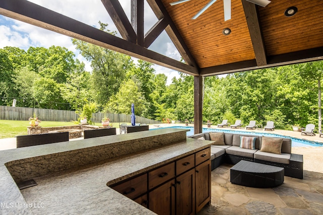 view of patio / terrace with fence, an outdoor kitchen, view of scattered trees, and an outdoor hangout area