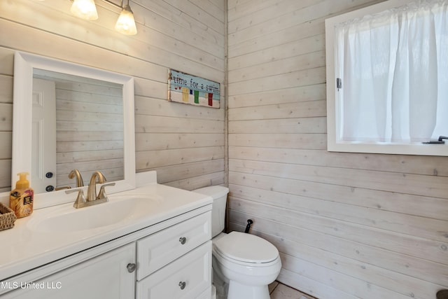 bathroom featuring wooden walls, toilet, and vanity