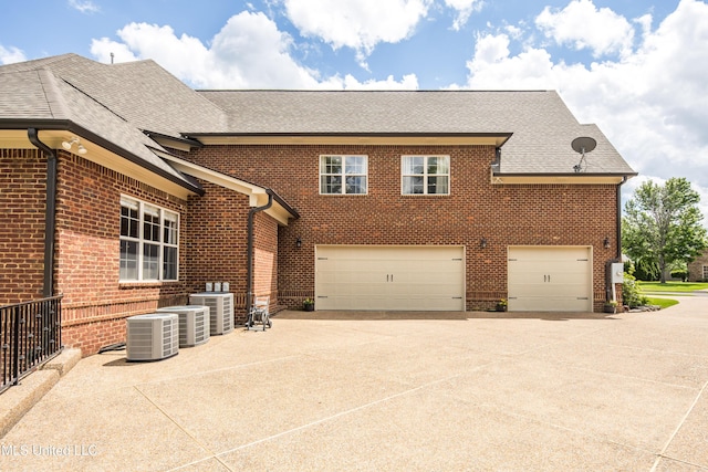 view of front facade featuring brick siding, concrete driveway, roof with shingles, an attached garage, and cooling unit