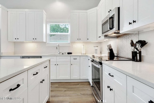 kitchen with light hardwood / wood-style floors, sink, white cabinetry, and stainless steel appliances