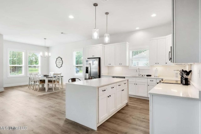 kitchen with a center island, hanging light fixtures, stainless steel fridge with ice dispenser, white cabinets, and light wood-type flooring