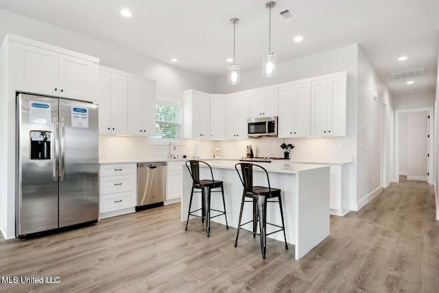 kitchen featuring white cabinetry, light hardwood / wood-style flooring, a kitchen island, and appliances with stainless steel finishes