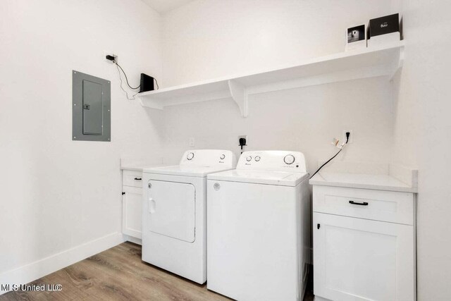 washroom featuring cabinets, electric panel, light hardwood / wood-style floors, and washing machine and clothes dryer