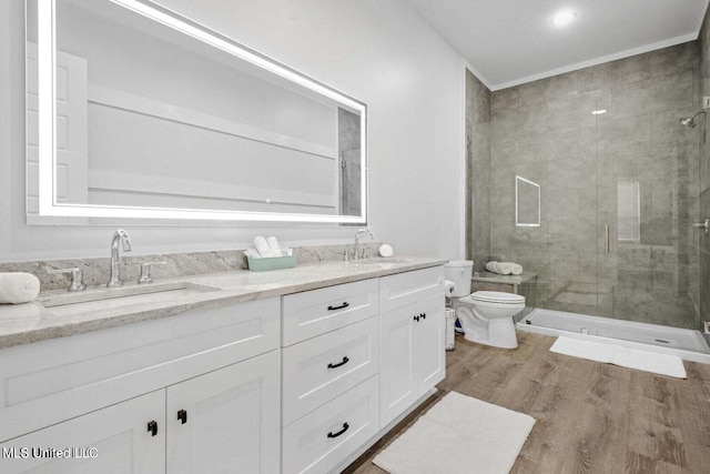 bathroom featuring vanity, wood-type flooring, a shower with shower door, and toilet