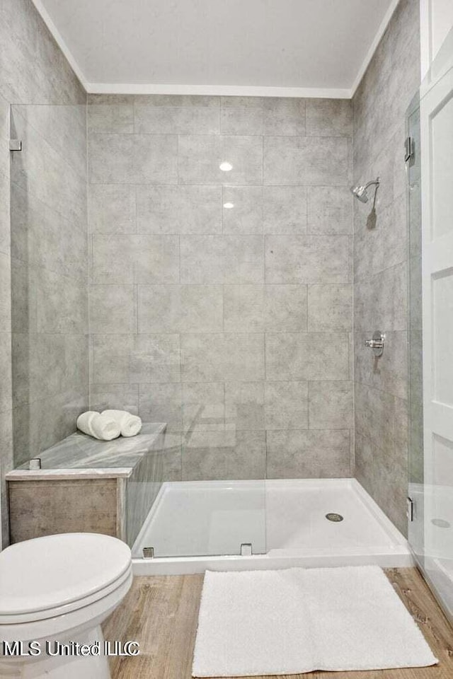 bathroom with hardwood / wood-style floors, toilet, crown molding, and walk in shower