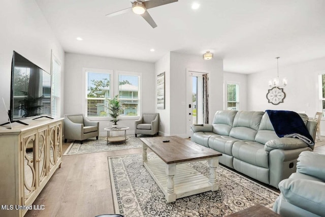 living room featuring ceiling fan with notable chandelier, light hardwood / wood-style flooring, and plenty of natural light