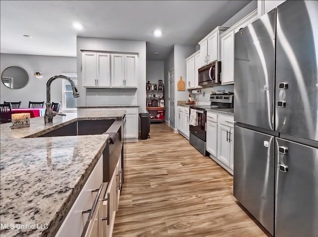 5065 Fairbury Way, Diberville, MS 39540 - kitchen with appliances with stainless steel finishes, light stone counters, light wood-type flooring, white cabinetry, and recessed lighting