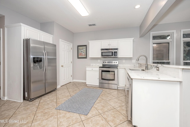 2204 Rue Beaux Chenes, Ocean Springs, MS 39564 - kitchen with appliances with stainless steel finishes, a peninsula, white cabinets, light tile patterned floors, and recessed lighting