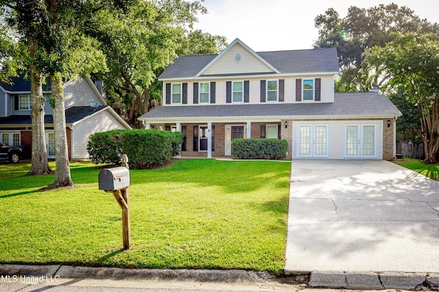 2204 Rue Beaux Chenes, Ocean Springs, MS 39564 - view of front of house with french doors, concrete driveway, a front yard, brick siding, and roof with shingles