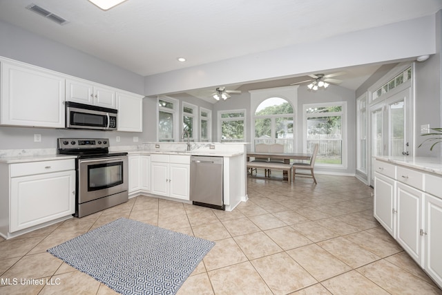 2204 Rue Beaux Chenes, Ocean Springs, MS 39564 - kitchen featuring appliances with stainless steel finishes, ceiling fan, white cabinetry, light tile patterned flooring, and lofted ceiling