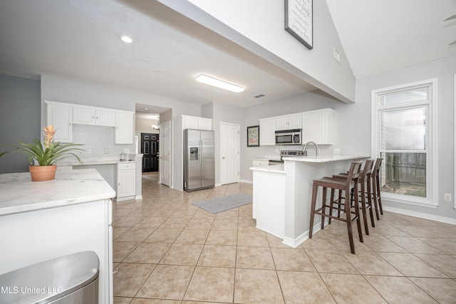 2204 Rue Beaux Chenes, Ocean Springs, MS 39564 - kitchen featuring stainless steel appliances, a peninsula, light tile patterned flooring, light countertops, and white cabinetry
