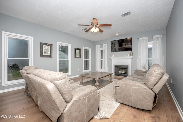 2204 Rue Beaux Chenes, Ocean Springs, MS 39564 - living room featuring ceiling fan, wood-type flooring, a fireplace, and a textured ceiling