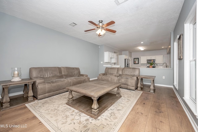 2204 Rue Beaux Chenes, Ocean Springs, MS 39564 - living room with ceiling fan, light wood-style floors, a textured ceiling, and healthy amount of natural light